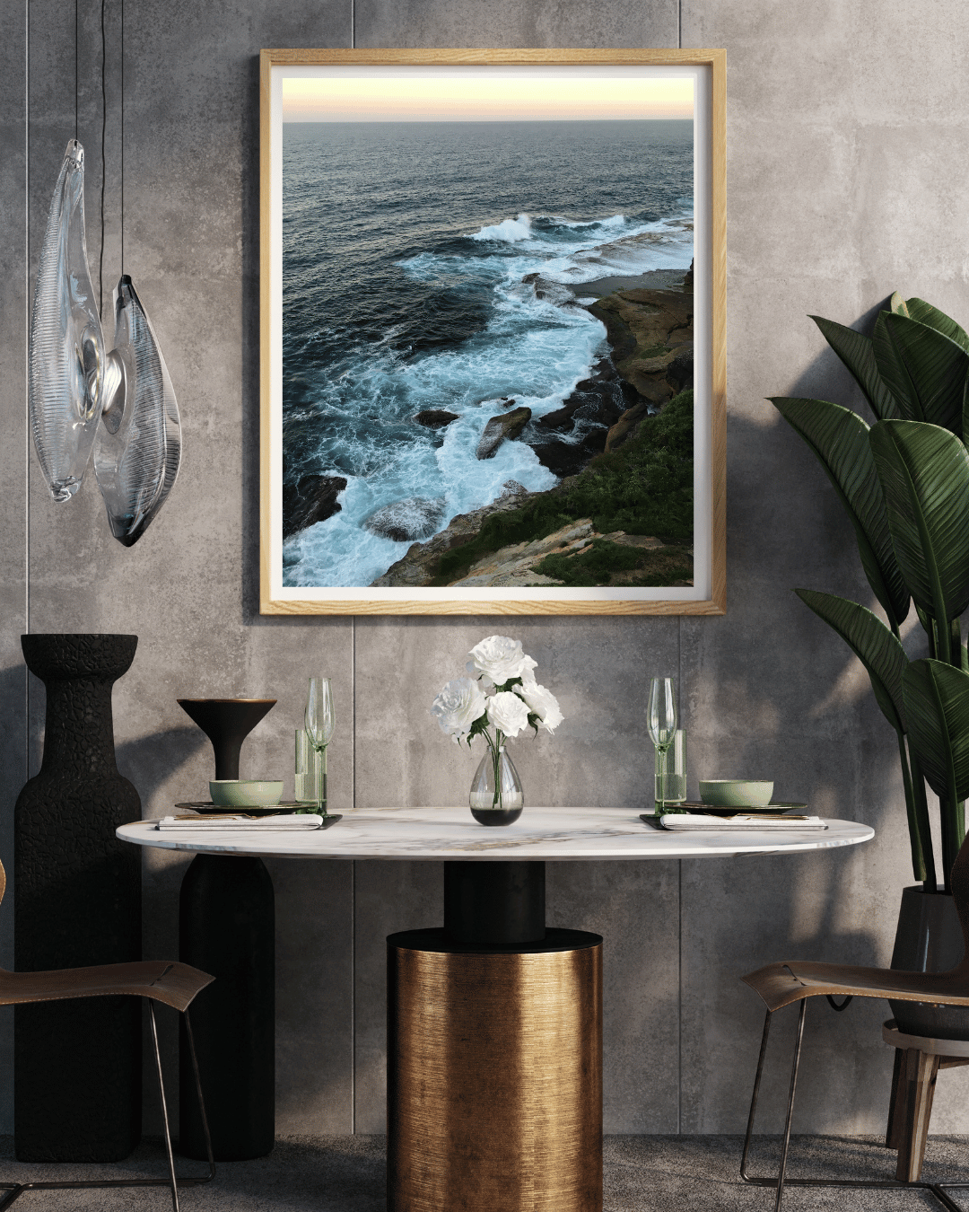 A framed coastal landscape photograph hanging on a textured gray wall above a dining table in a modern interior setting.