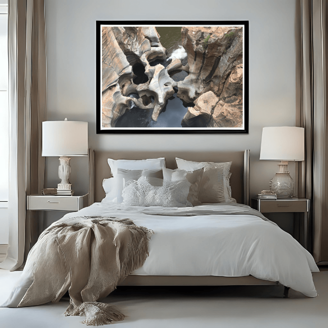 A framed wall art print depicting the natural wonder of sculpted rock formations in Bourke's Potholes, South Africa, displayed above a neatly made bed in a modern, symmetrically styled bedroom.