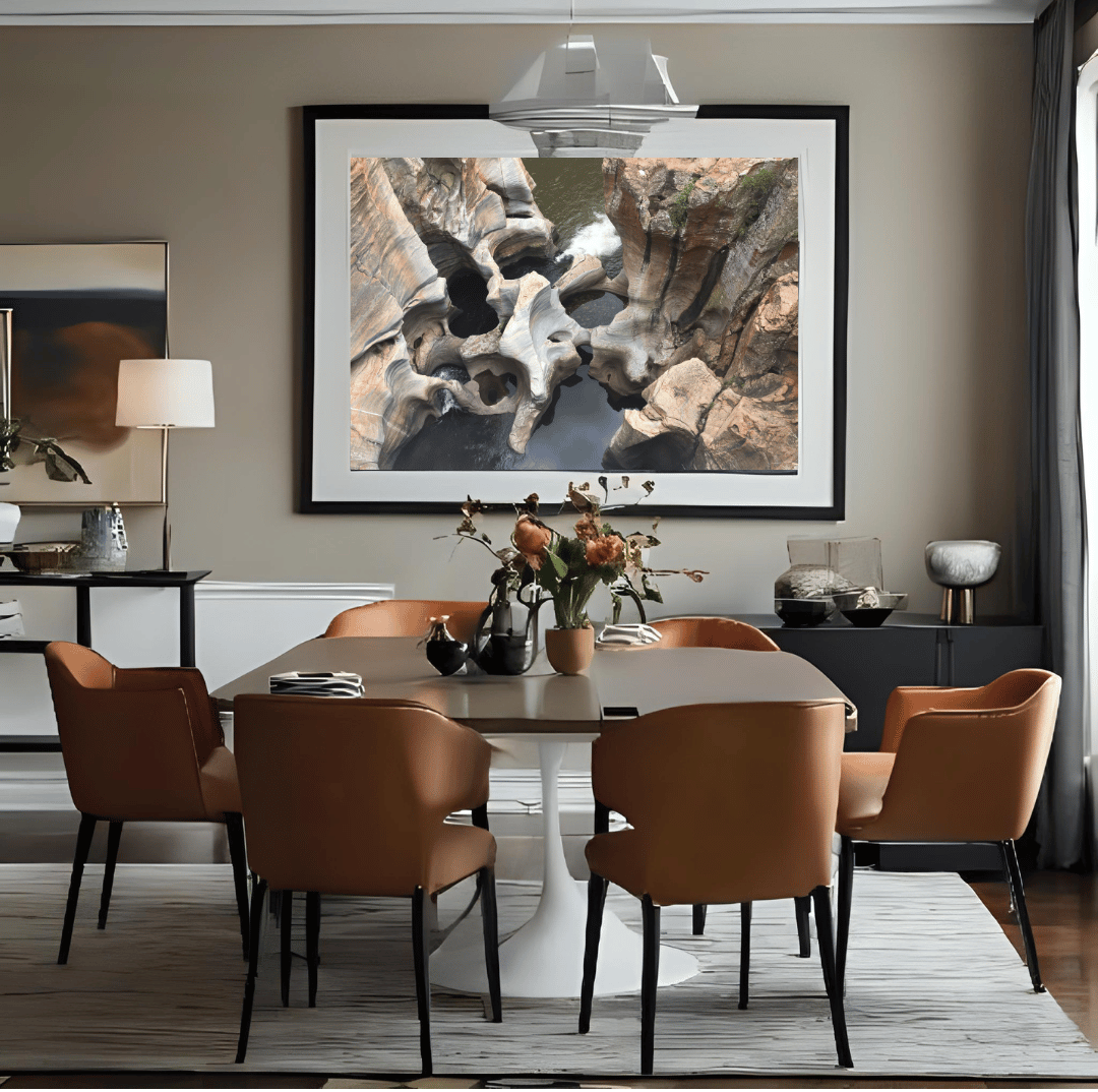 A large framed abstract art print featuring the natural wonder of sculpted rock formations in Bourke's Potholes, South Africa, displayed on a beige wall above a dining table with brown chairs in a modern dining room setting.