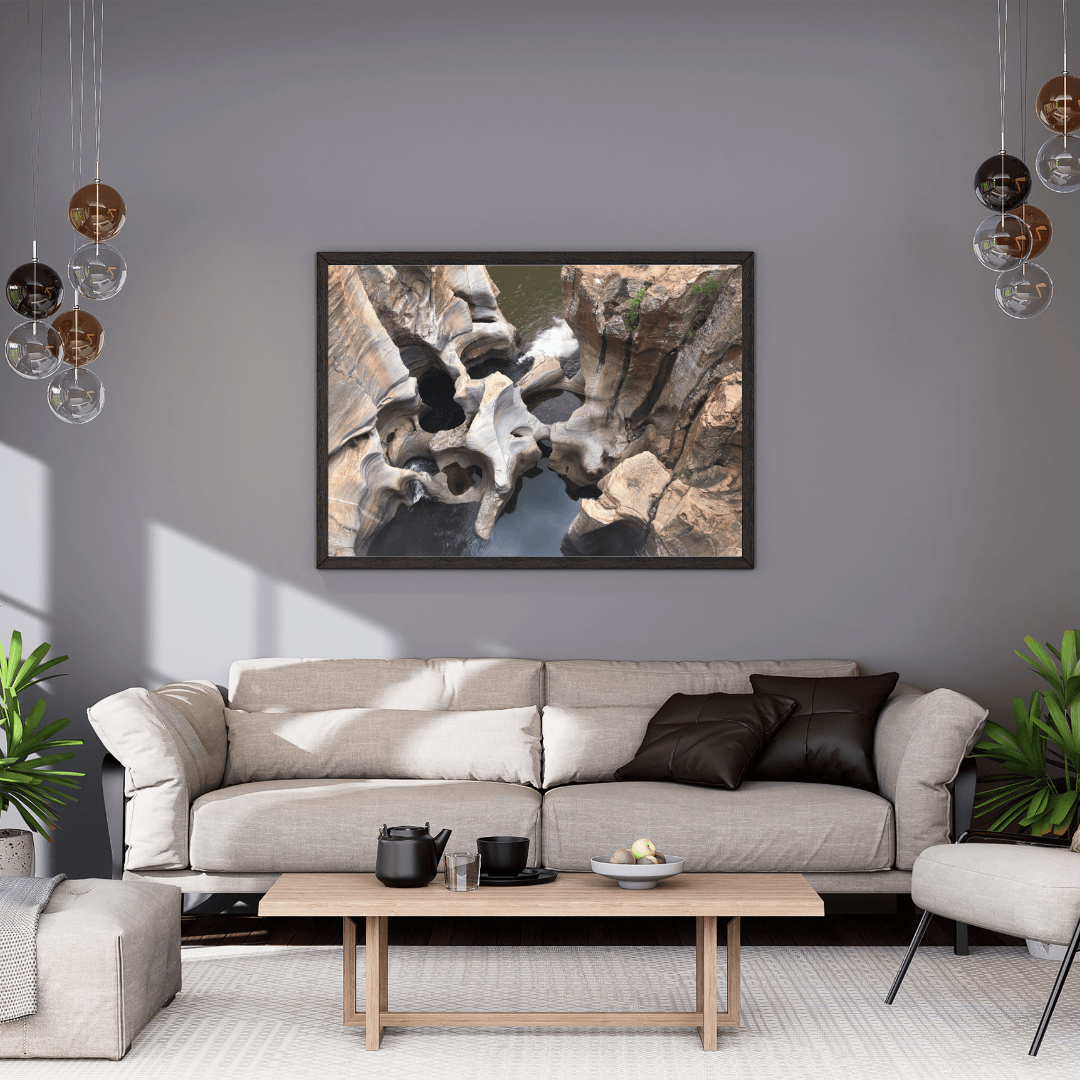 A framed art print depicting the natural wonder of sculpted rock formations in Bourke's Potholes, South Africa, displayed on a gray wall above a modern beige sofa in a styled living room.