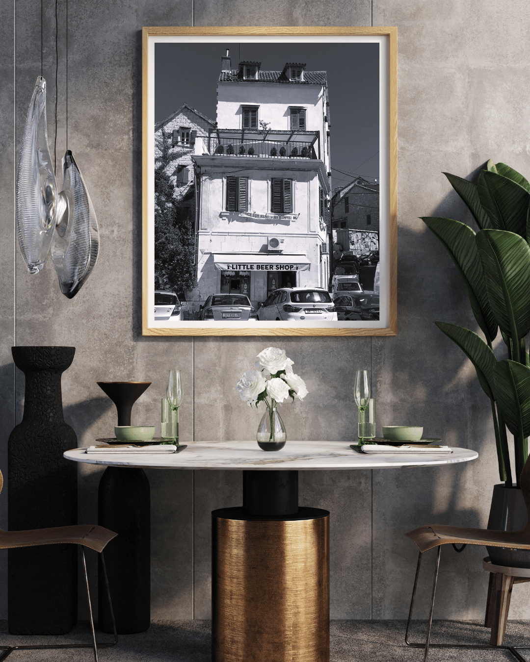 A framed black and white architectural photograph of a historic building in Paris, displayed on a textured gray wall above a dining table in a modern, stylishly decorated room.