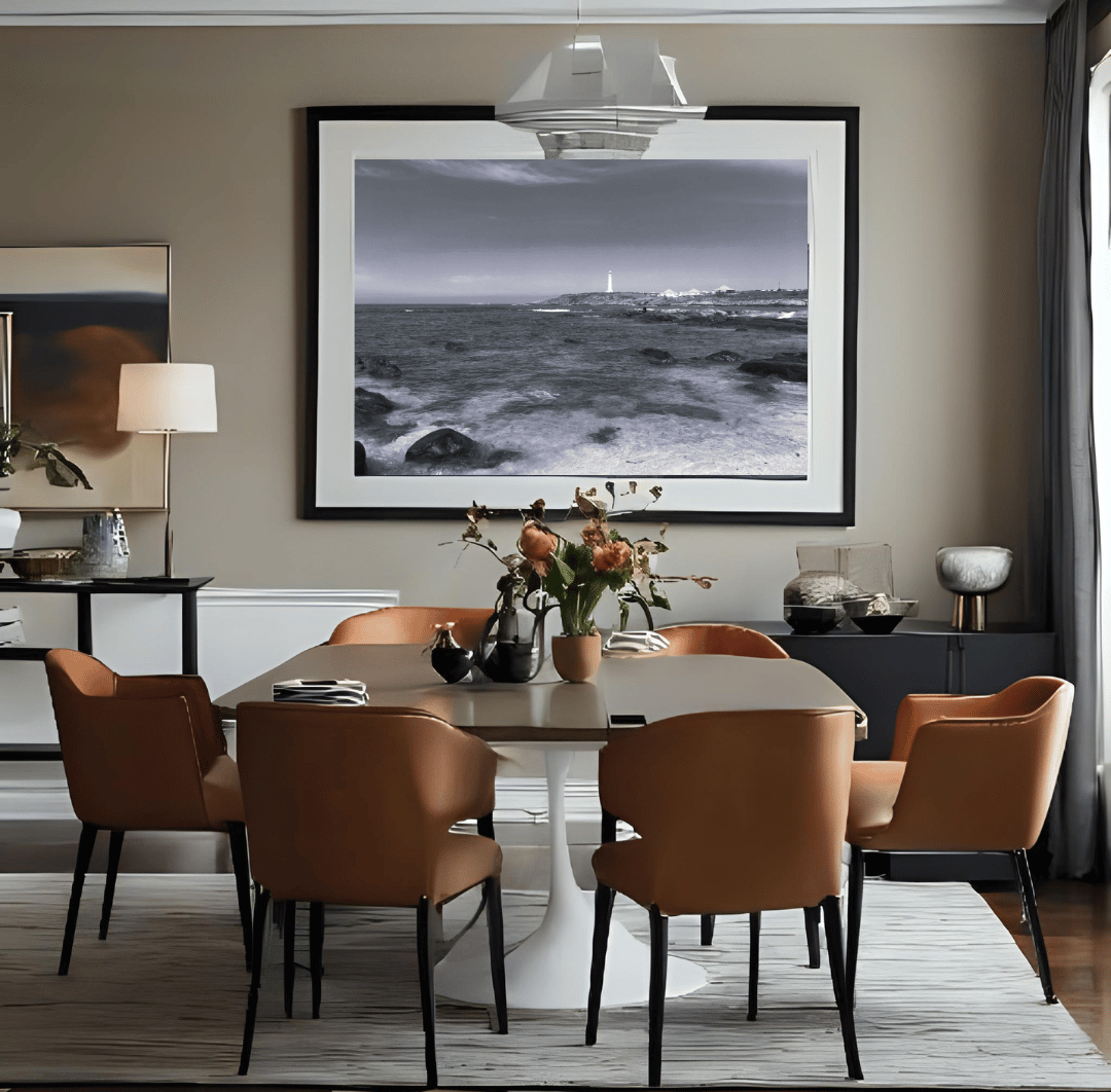 A large black and white framed wall art print depicting a coastal seascape with waves, hung in a dining room above a modern dining table and six tan upholstered chairs.