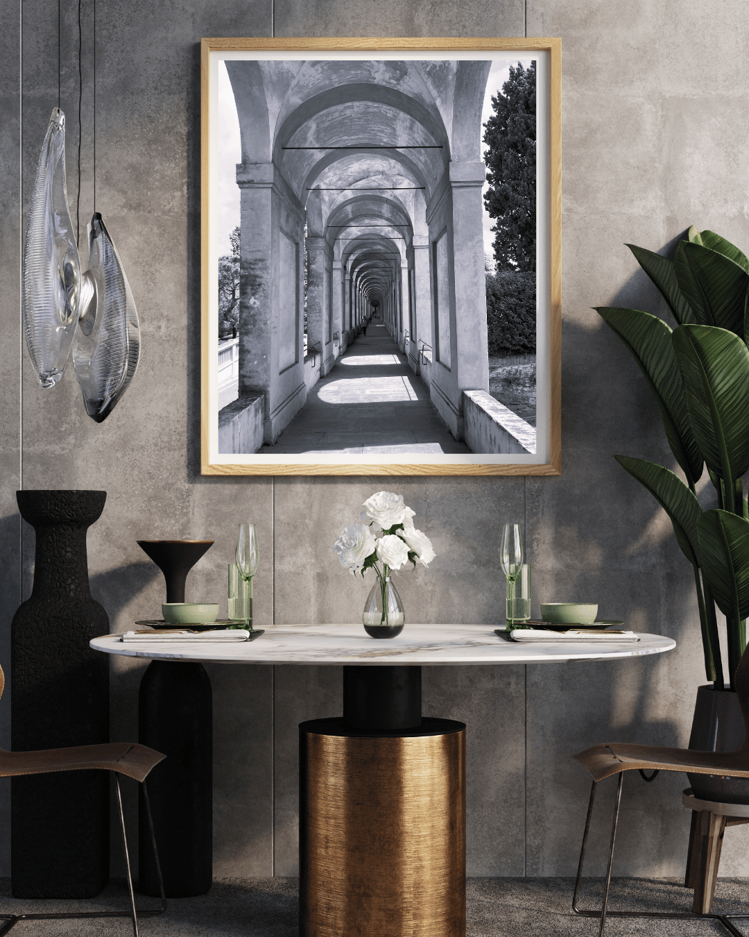 A framed black and white architectural art print depicting a stone archway corridor, displayed on a textured gray wall above a dining table in a modern styled room.