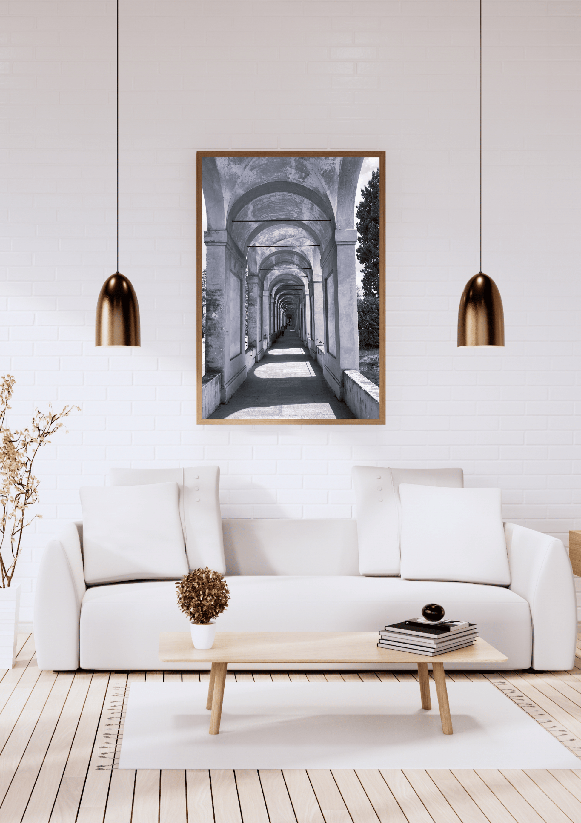 A framed black and white art print depicting an arched corridor, displayed on a white brick wall above a modern white sofa in a styled living room.
