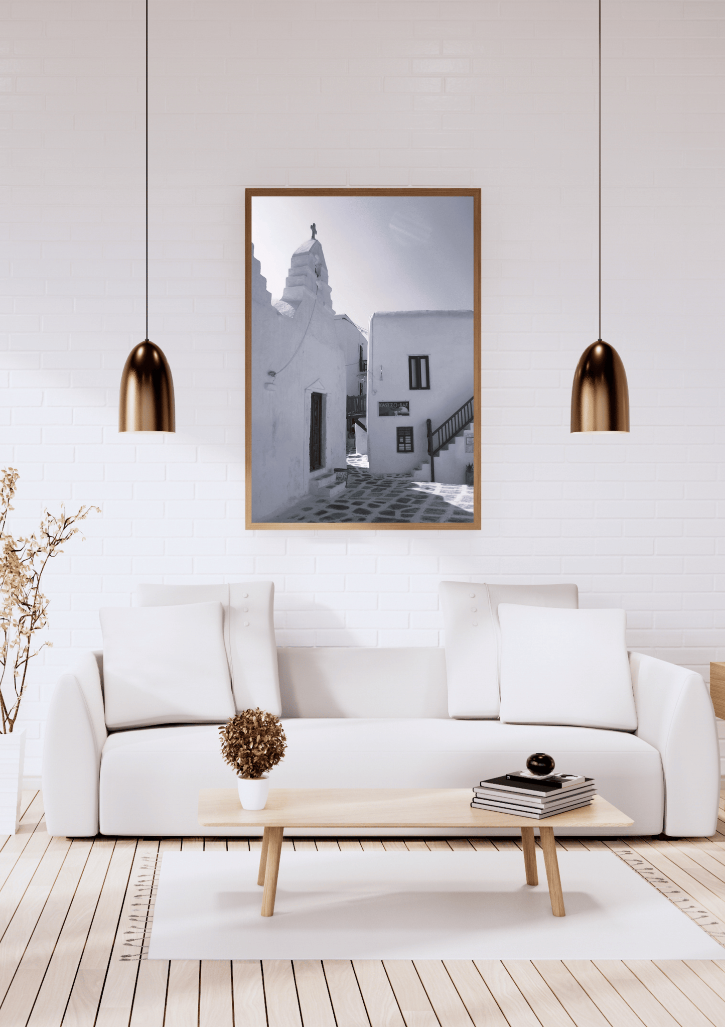 A framed black and white architectural photograph of a Mediterranean street scene hangs on a white brick wall above a modern white sofa in a bright, minimalist living room.