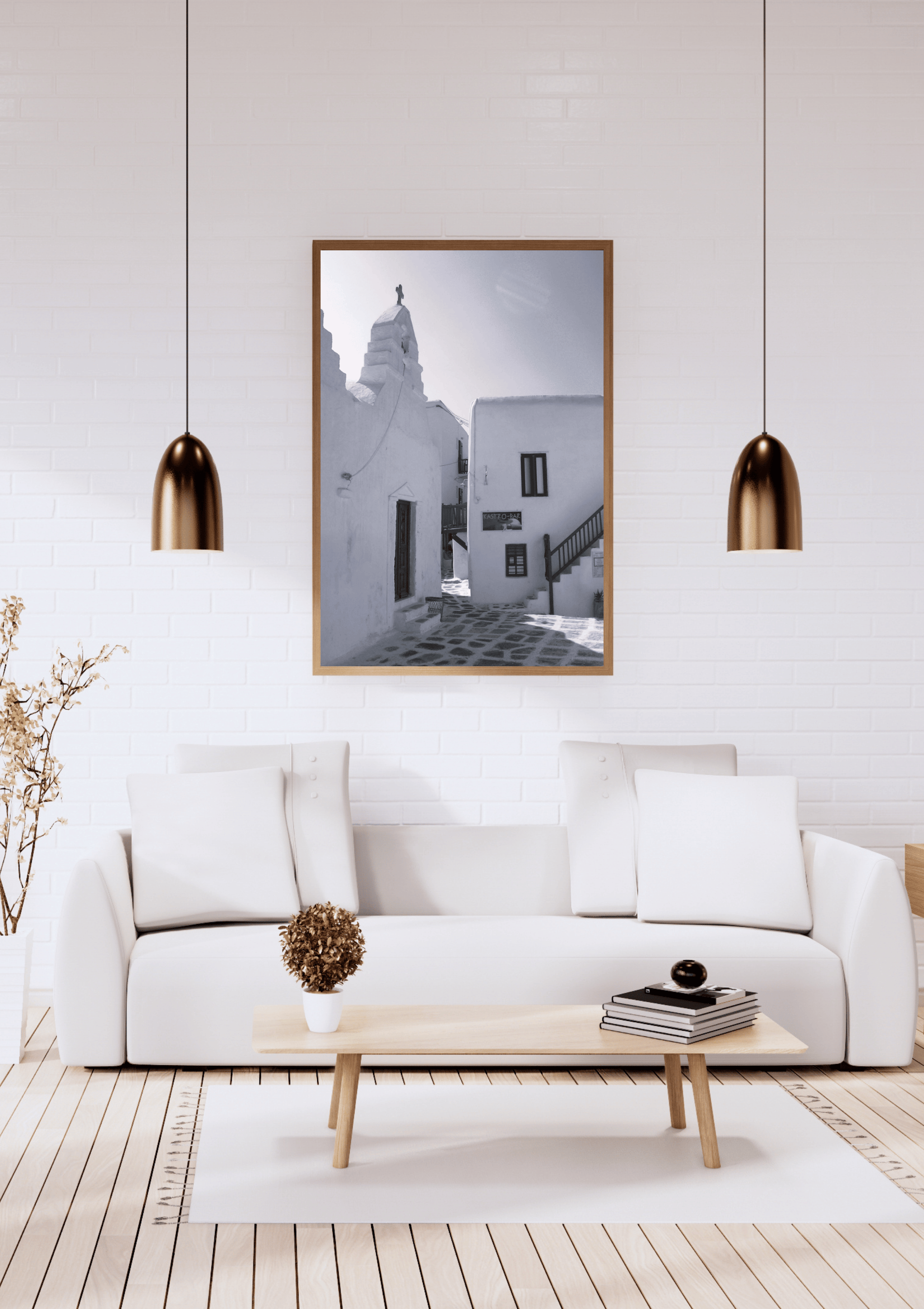 A framed black and white architectural photograph of a Mediterranean street scene hangs on a white brick wall above a modern white sofa in a bright, minimalist living room.